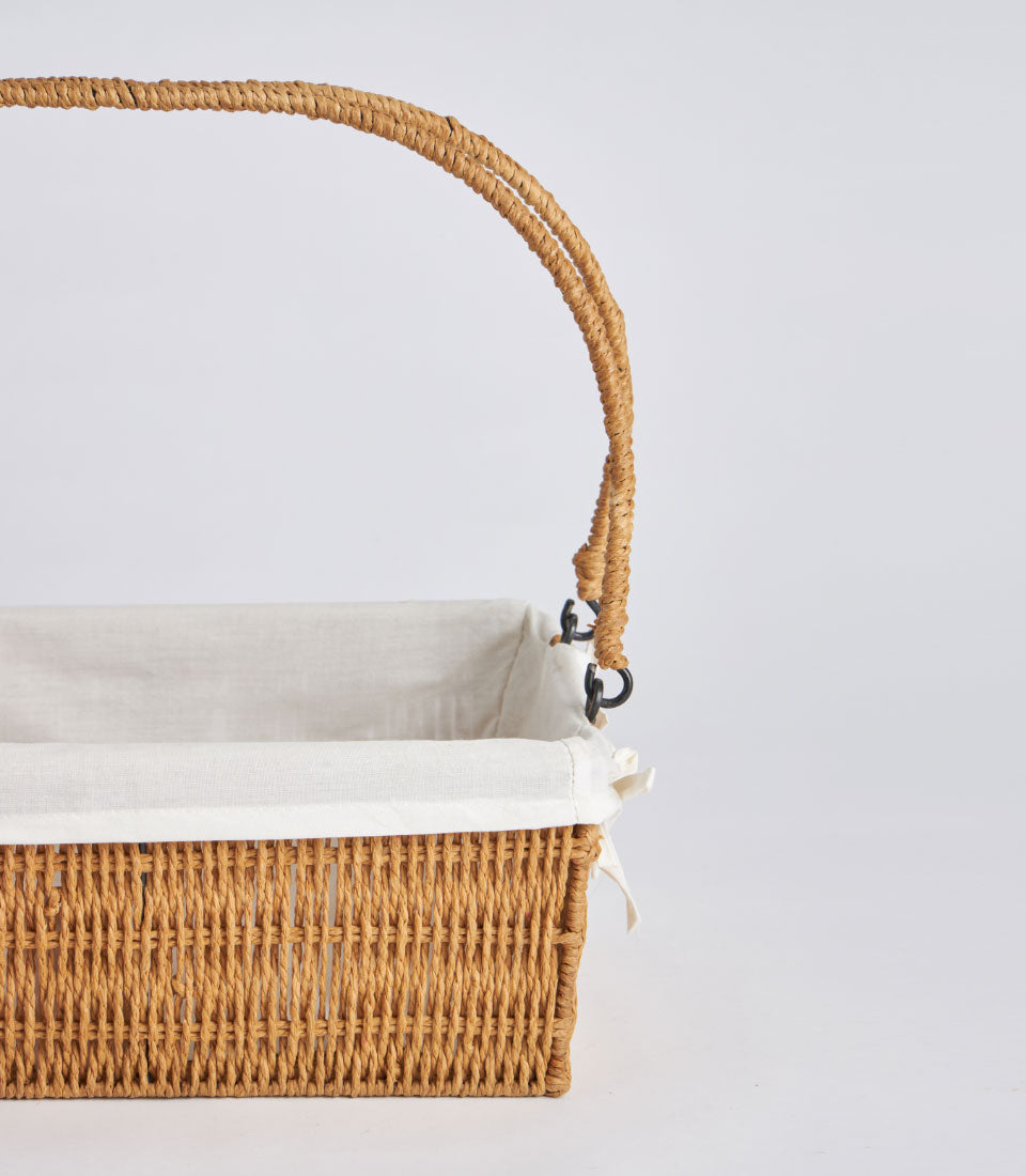 Handwoven rectangular wicker basket with dual handles and natural linen lining