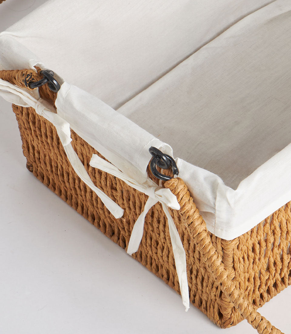 Handwoven rectangular wicker basket with dual handles and cream linen liner