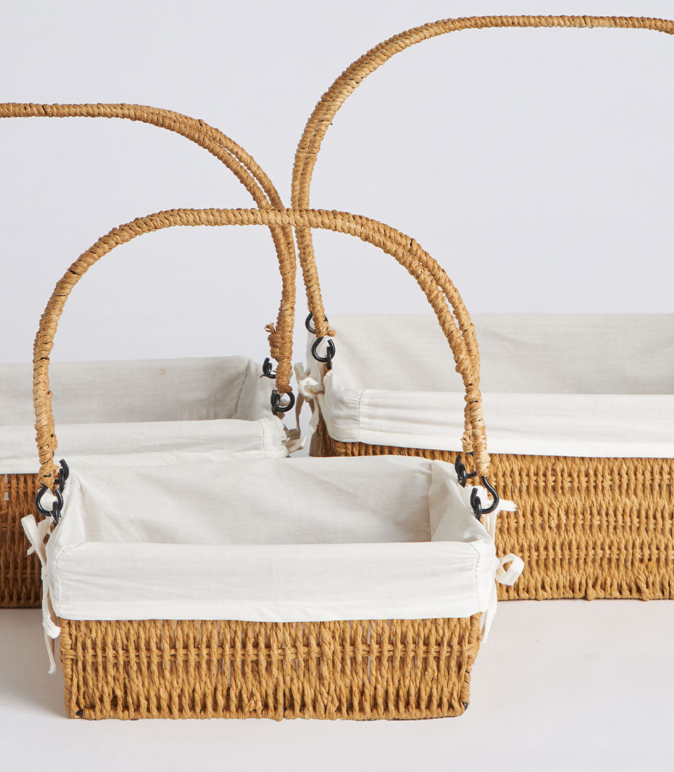 Light brown wicker baskets with dual handles and removable white linen liners