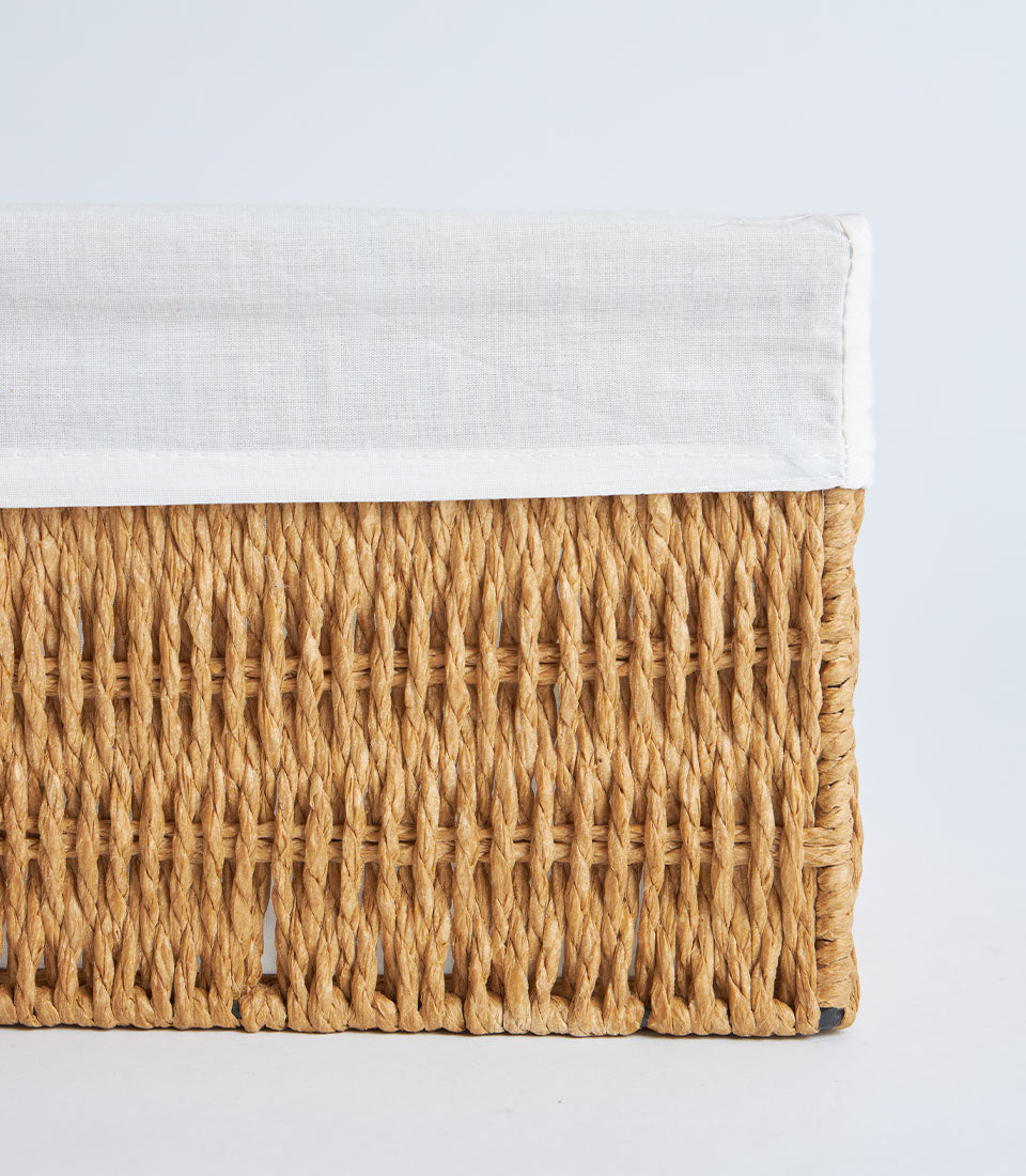 Handwoven rectangular wicker basket with white linen liner in natural tan raffia