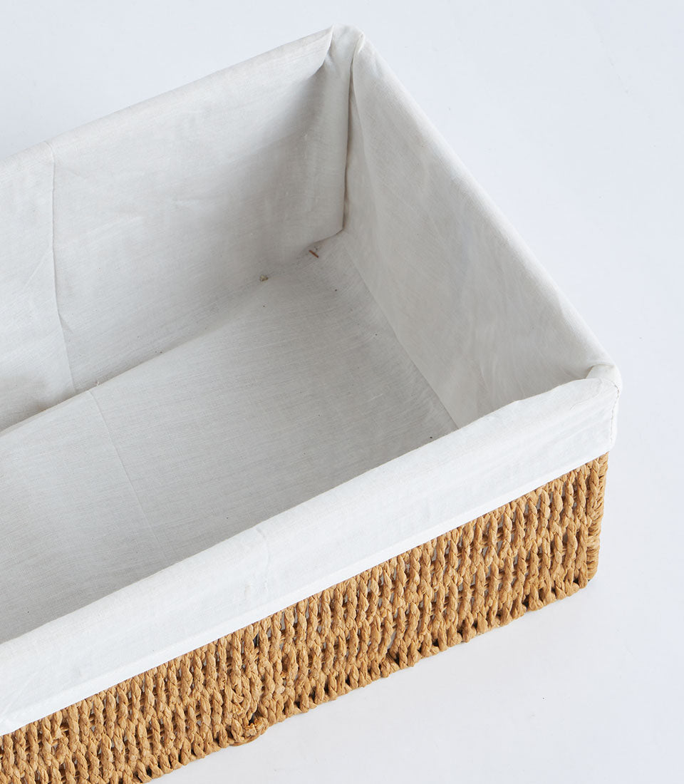 Handwoven rectangular wicker storage basket with natural seagrass exterior and cream fabric liner
