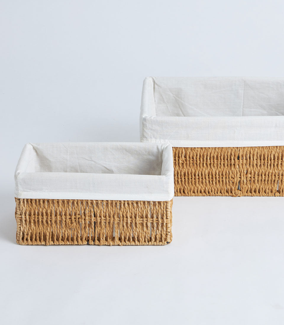 Handwoven natural wicker storage baskets with white linen liners, nested pair in warm tan