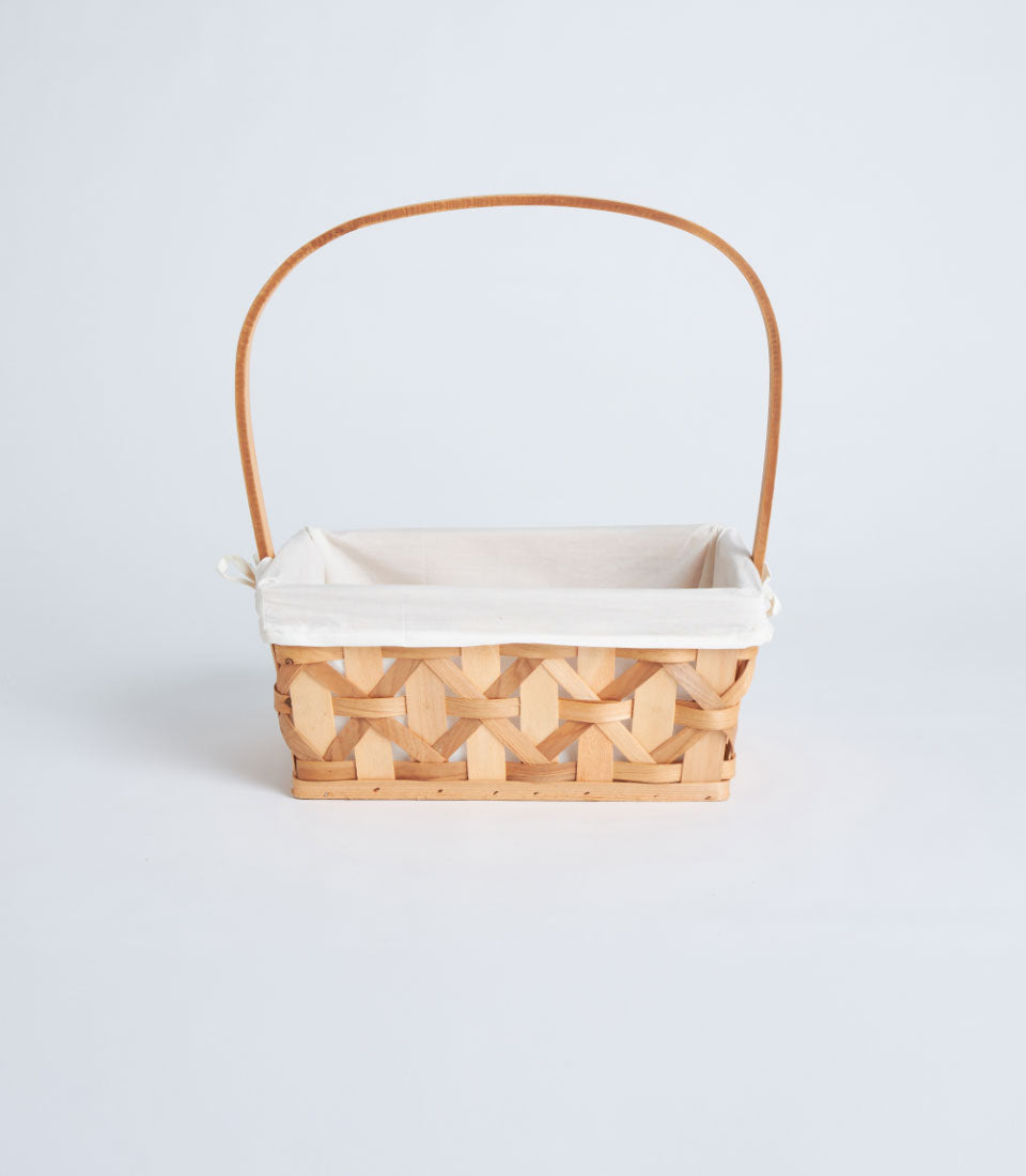 Handwoven rectangular wicker basket with tall handle and white fabric lining