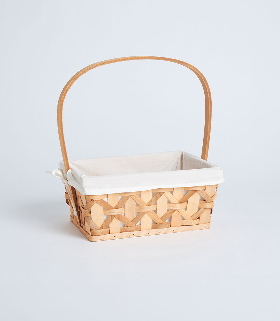 Light woven rectangular basket with tall handle and cream fabric lining, ready for luxury gift curation