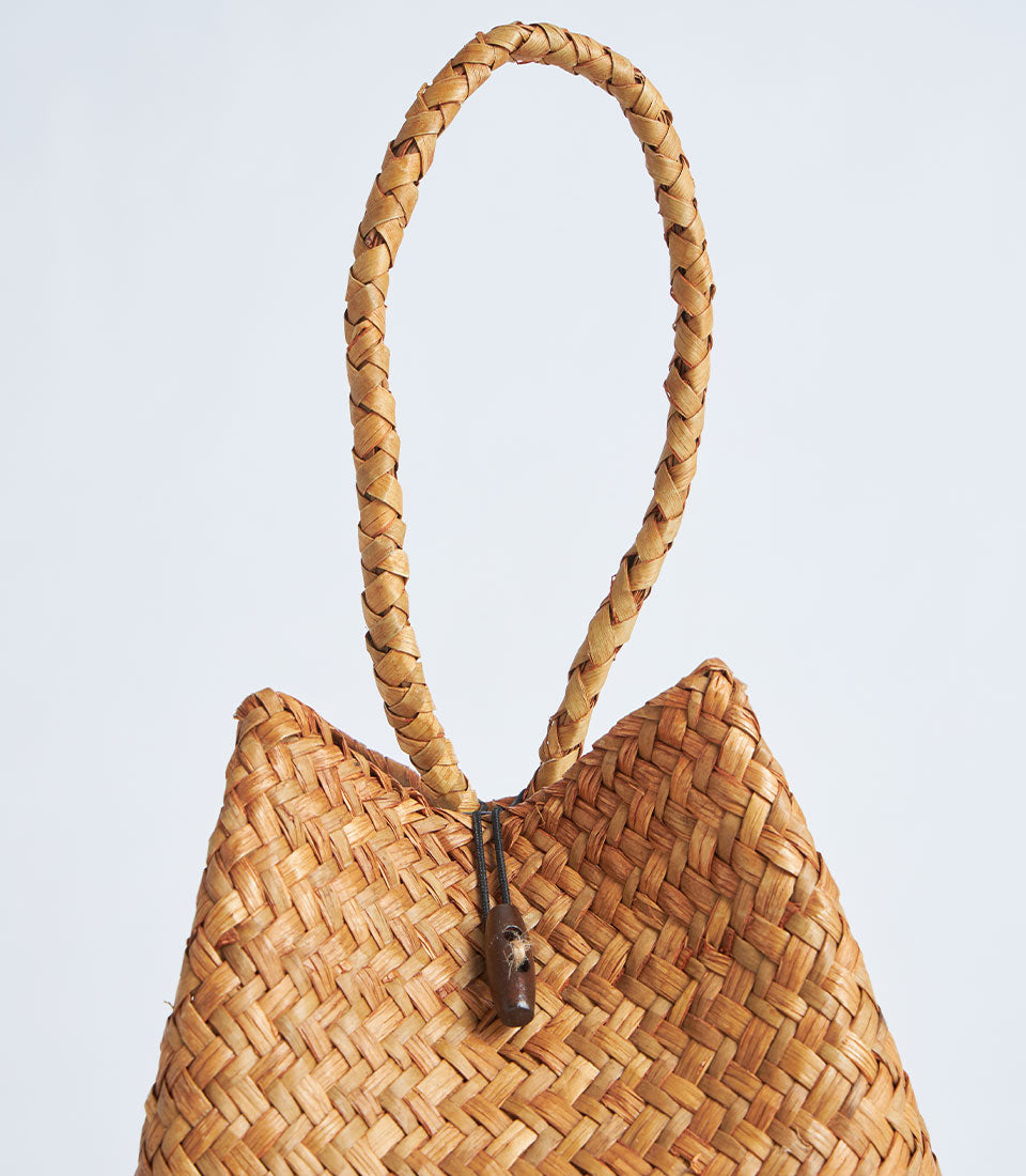 Natural woven straw gift basket with braided rope handle and red tassel closure