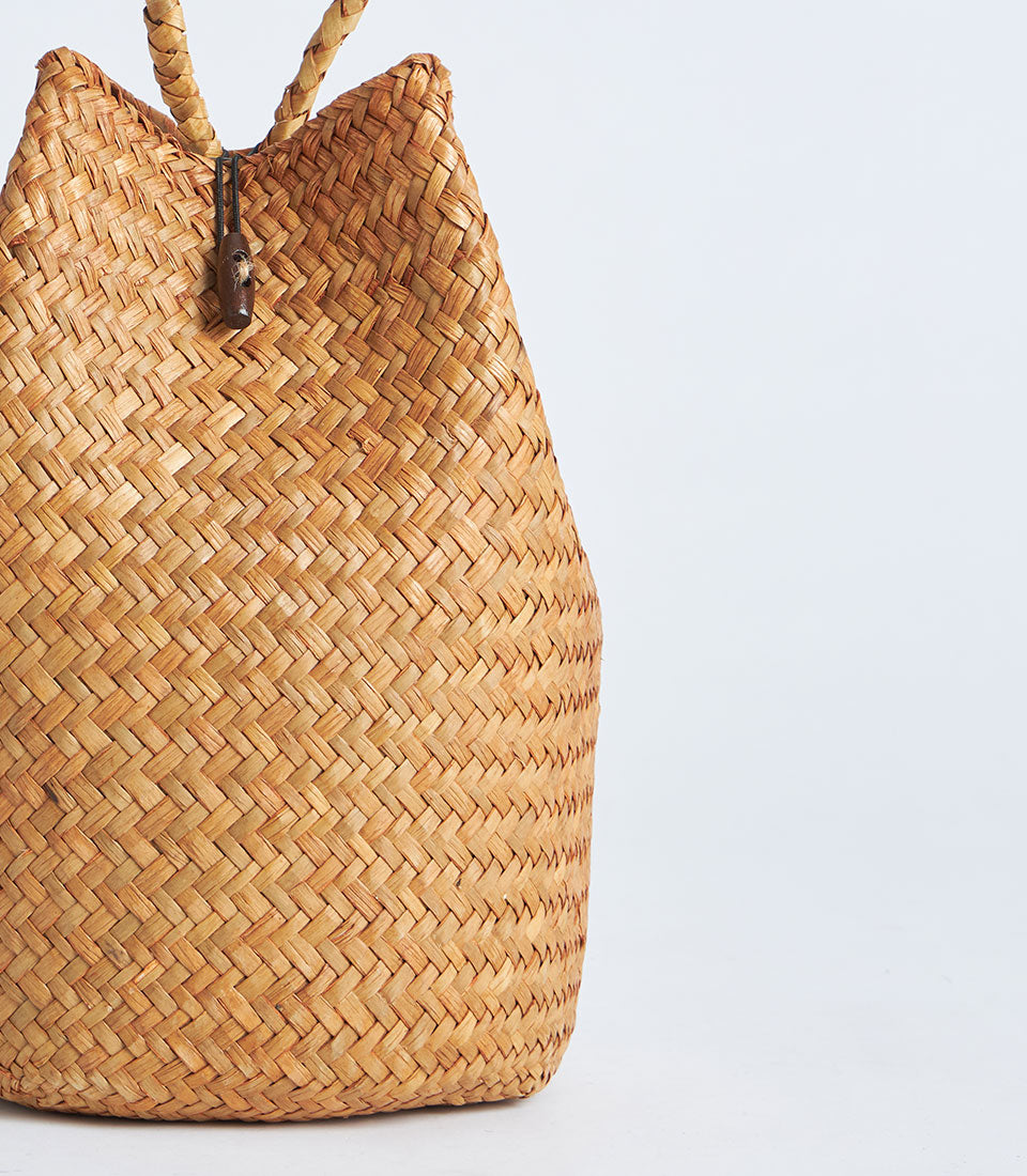 Natural straw gift basket with rope handle, woven in light brown with red tassel detail