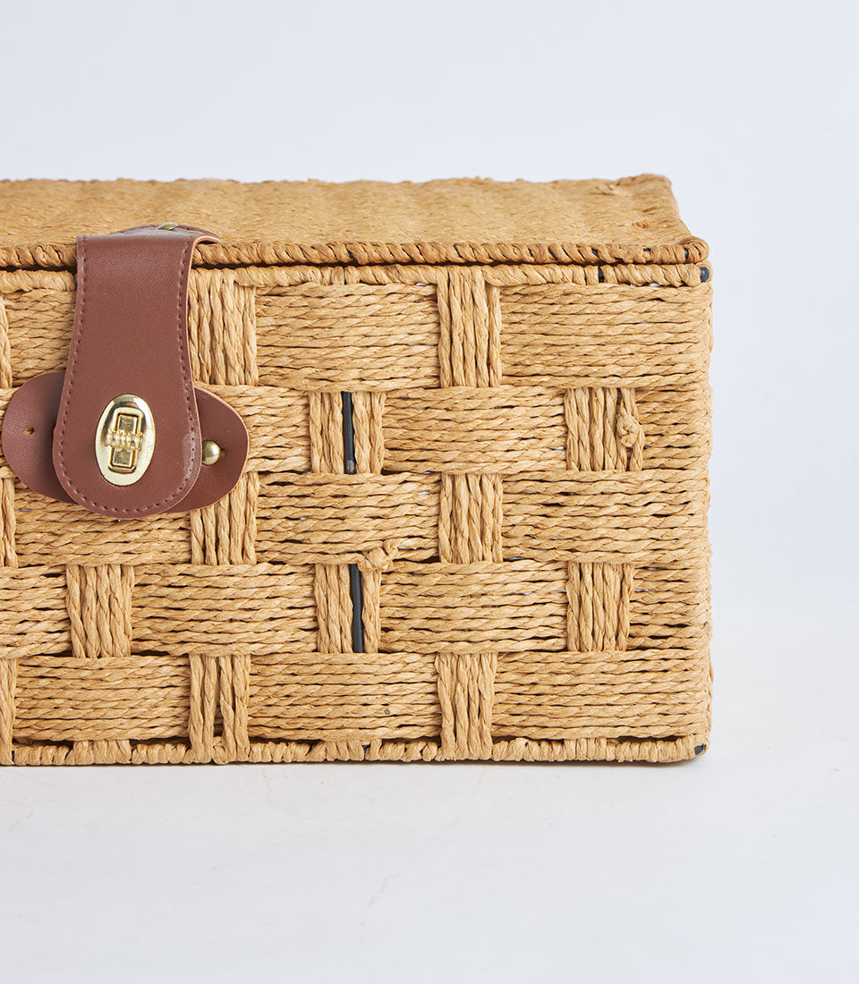 Light brown woven straw storage basket with leather lock closure and braided lid