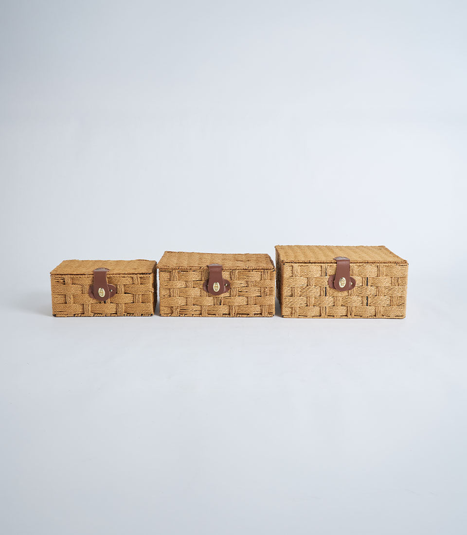 Three woven storage baskets with leather lock closures in graduated sizes