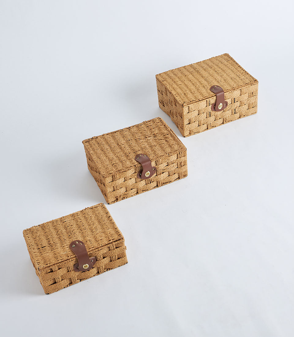 Woven natural fiber storage baskets with leather lock straps and gold metal closures