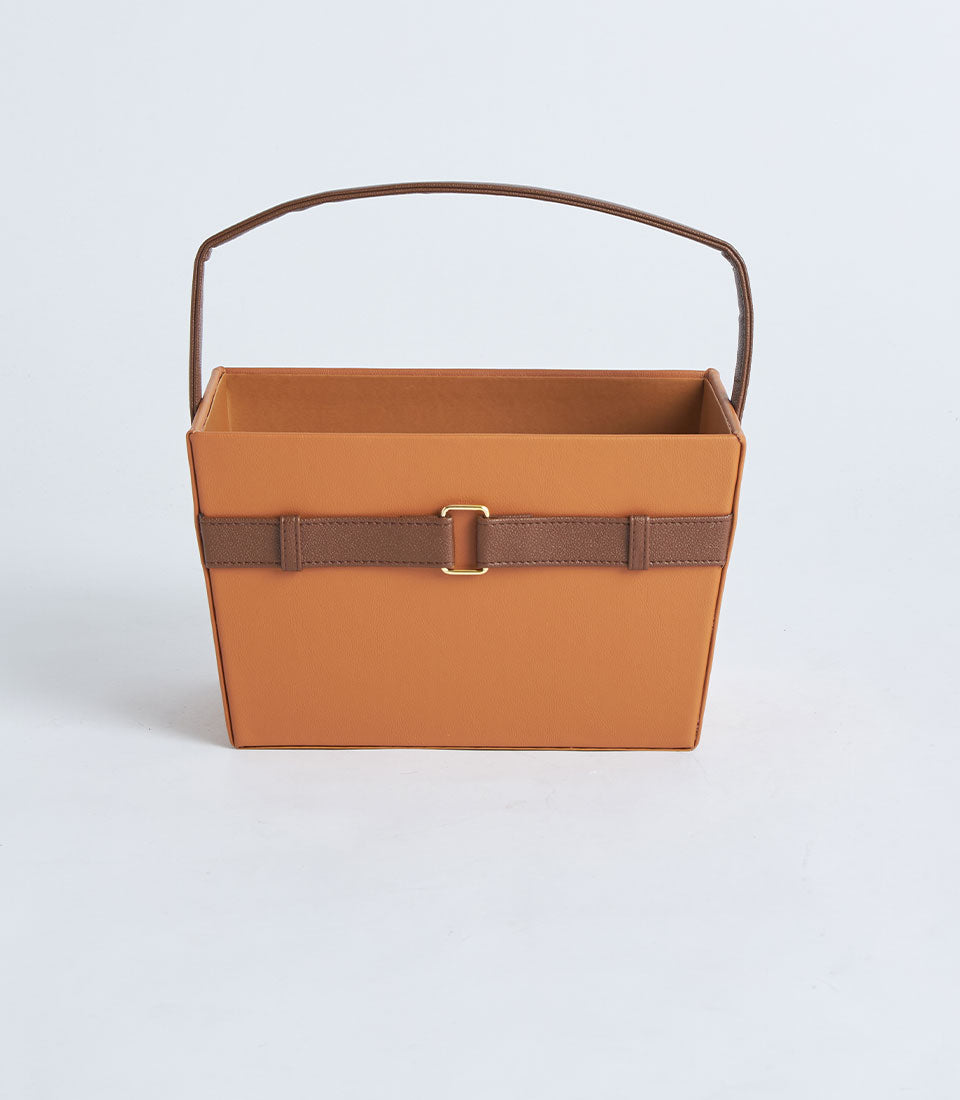 Tan leather gift basket with dark brown handle strap and gold buckle closure