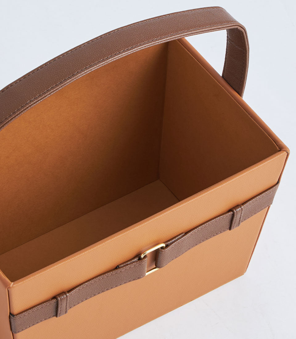 Tan faux leather gift basket with dark brown handle strap and gold buckle detail