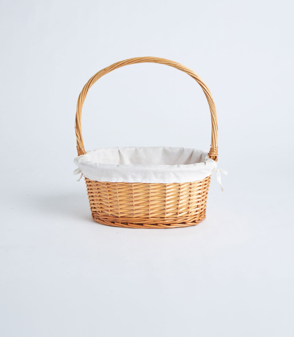 Natural wicker oval gift basket with cream fabric lining and arched handle