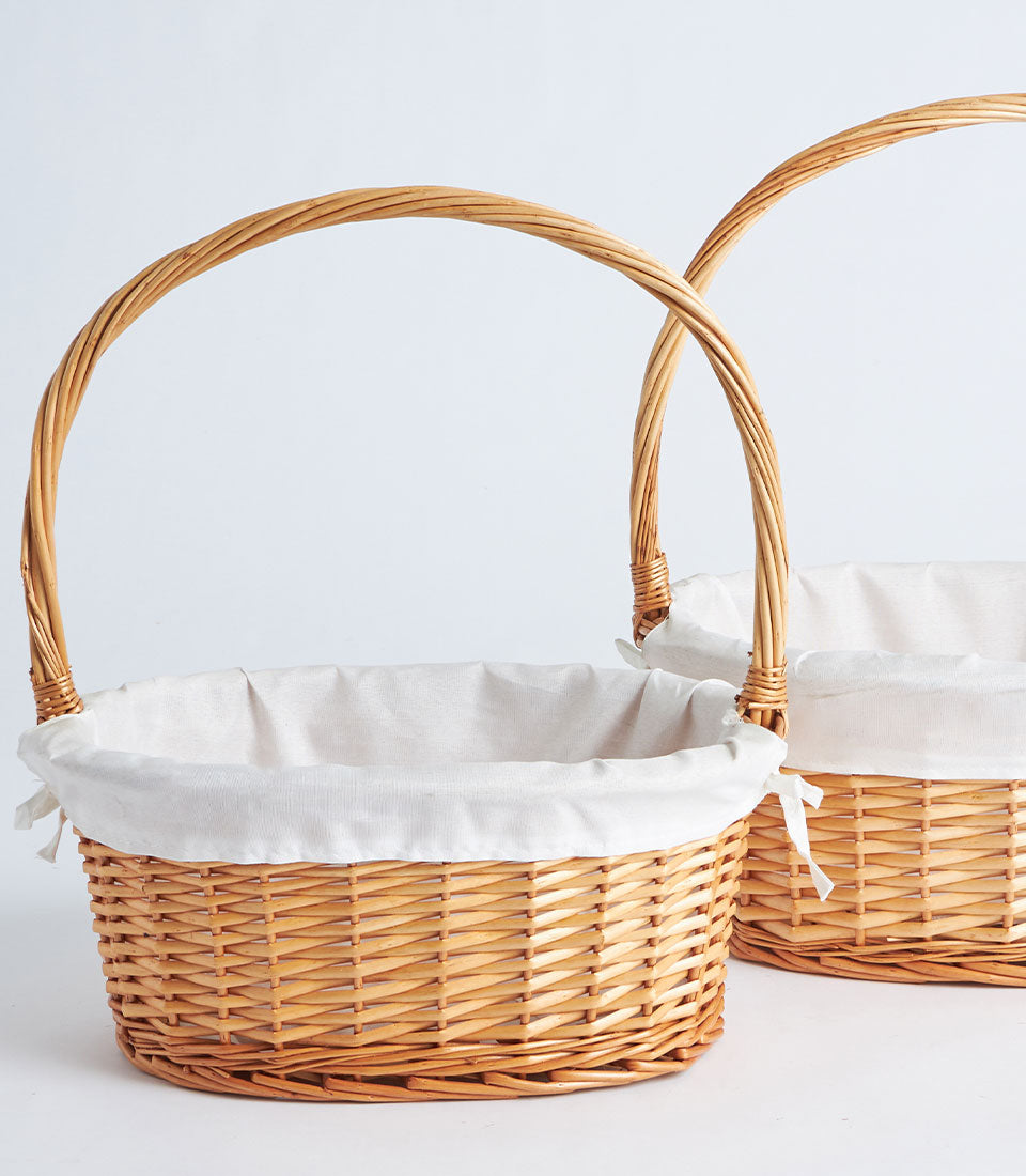 Light brown wicker gift baskets with white fabric liners and twisted handles for premium gifting
