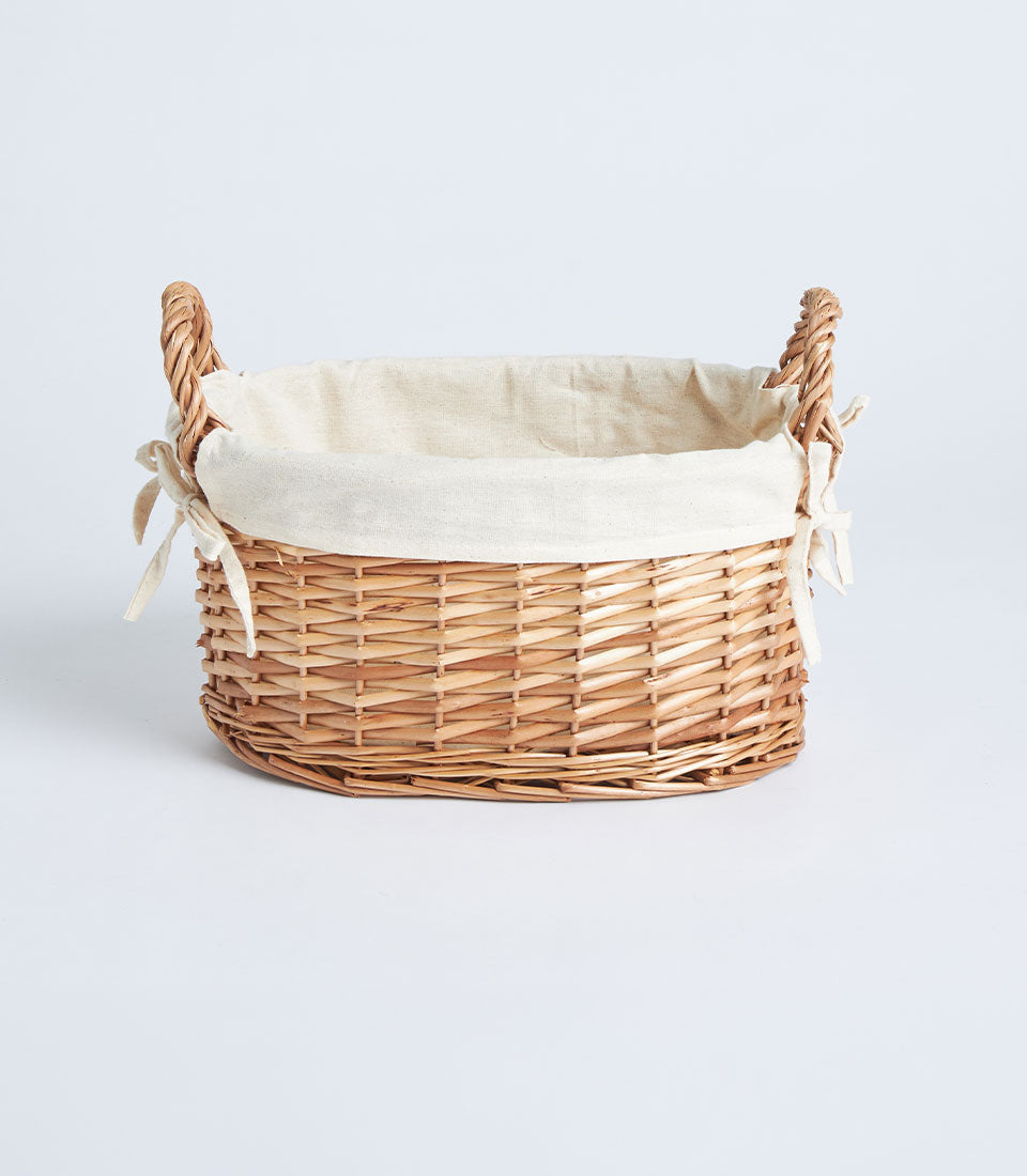 Light brown handwoven wicker basket with cream fabric lining and braided side handles