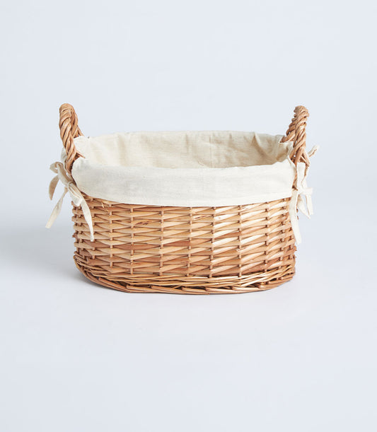 Light brown handwoven wicker basket with cream fabric lining and braided side handles
