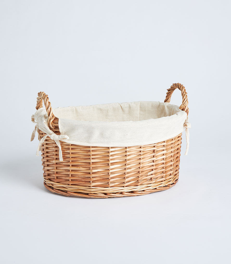 Handwoven oval wicker basket with cream fabric lining and twisted handles