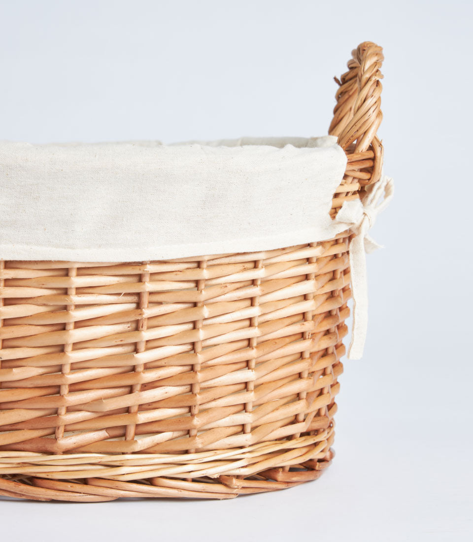 Light brown wicker gift basket with cream fabric lining and side handles