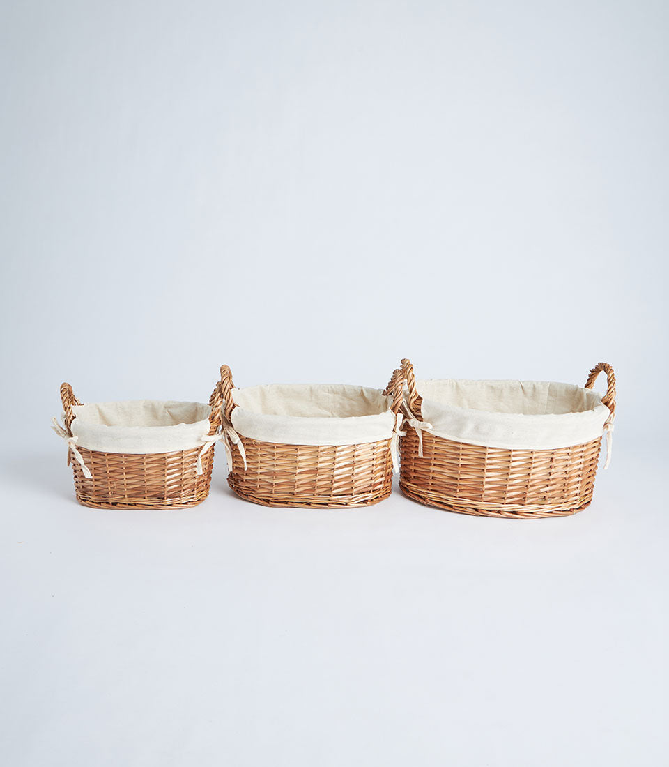 Natural woven oval baskets with cream fabric liners in three sizes, ready for luxury gift hampers