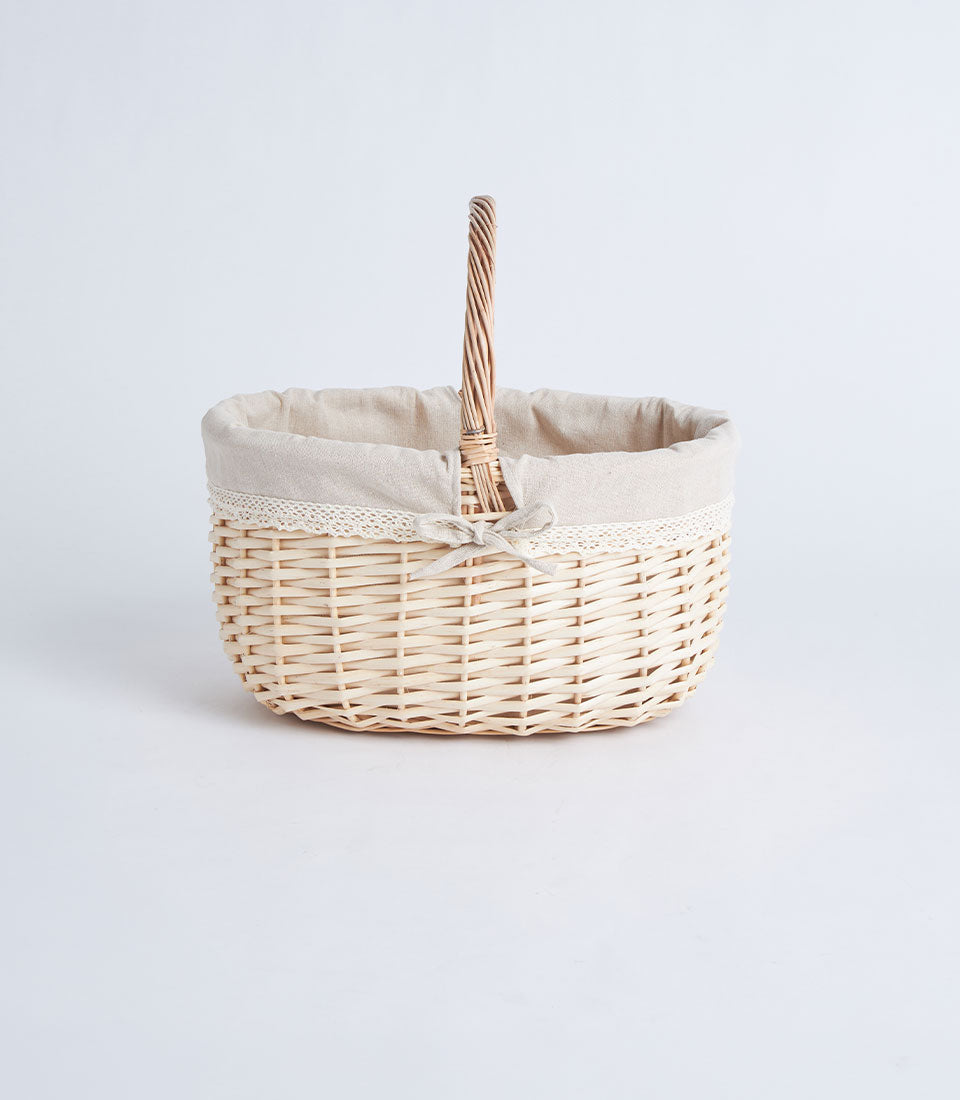 Handwoven light wicker oval basket with lace-lined interior and fabric bow handle