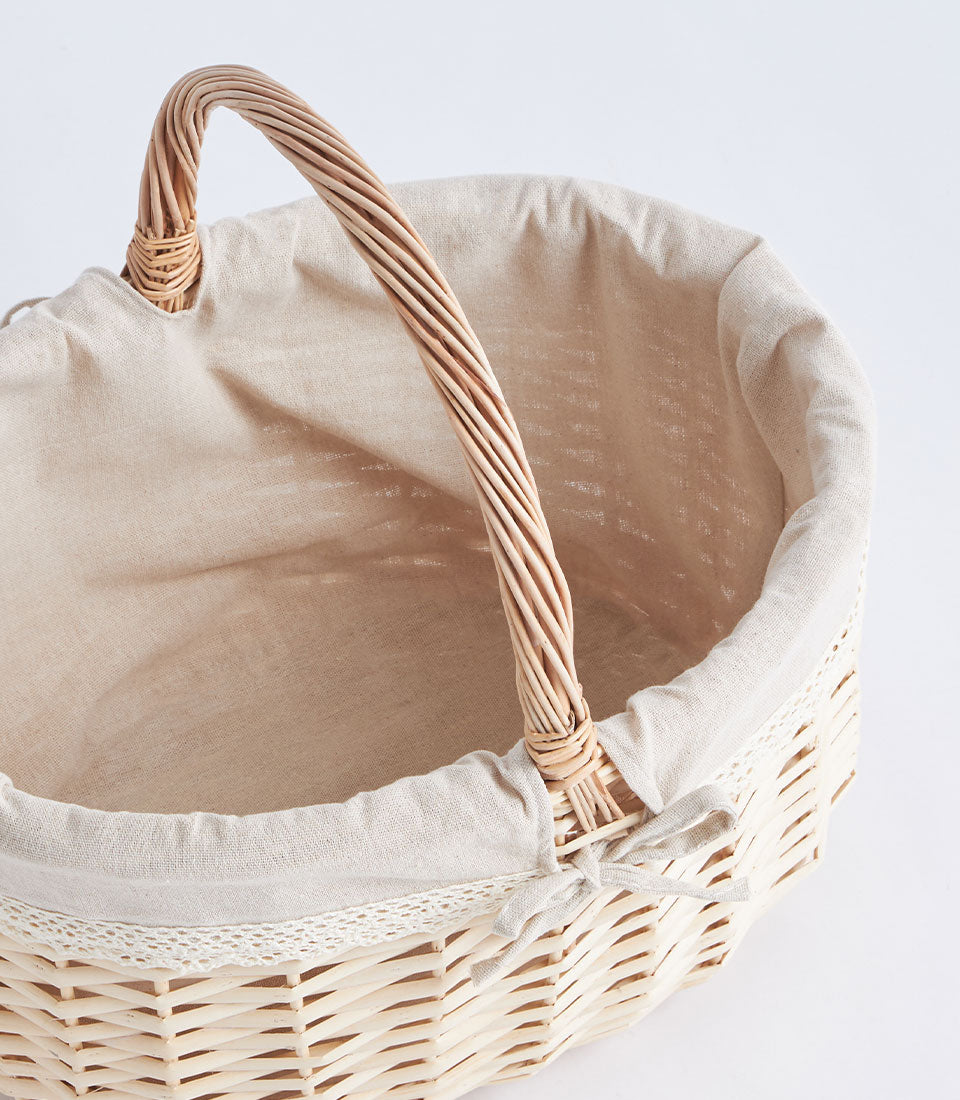 Natural wicker fruit and flower basket with beige fabric liner and arched handle