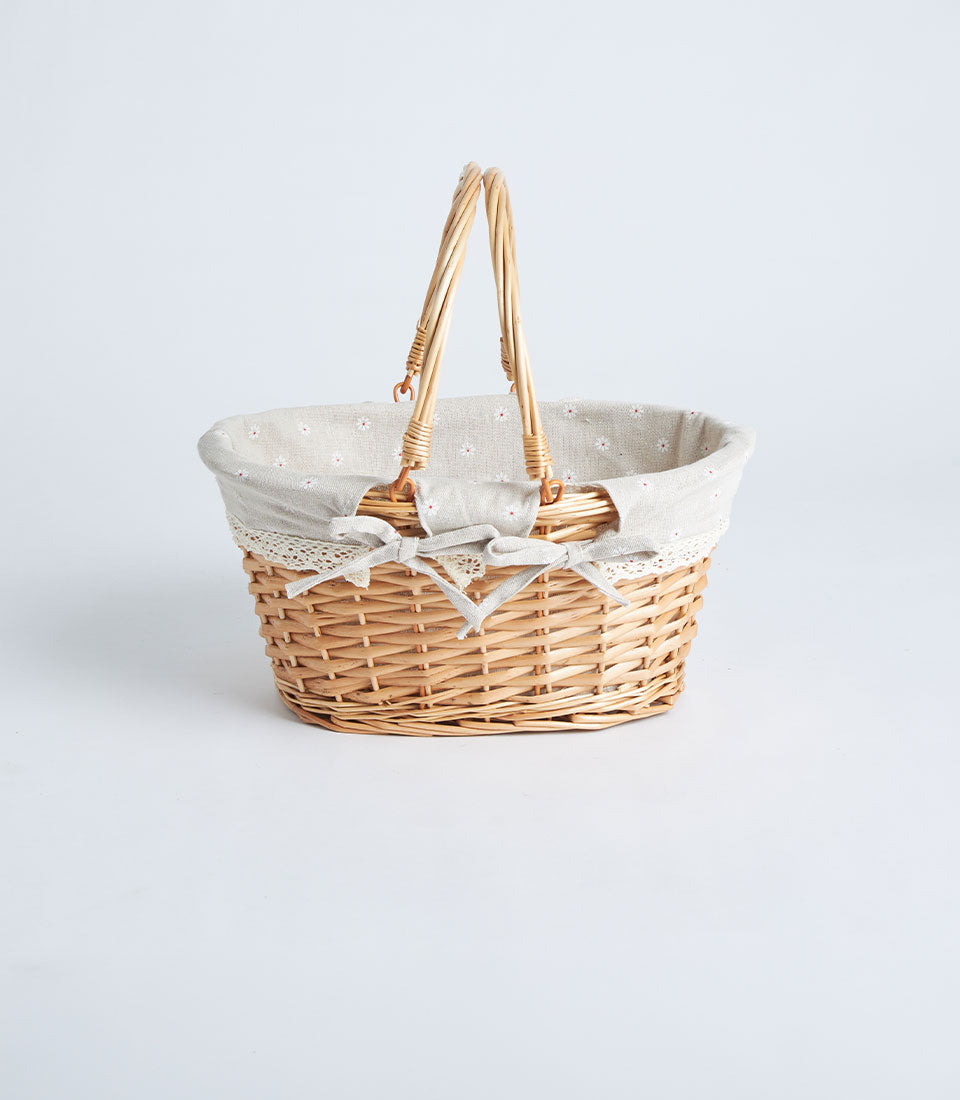 Light brown handwoven oval wicker basket with fabric lining, white floral pattern, and double fabric handles