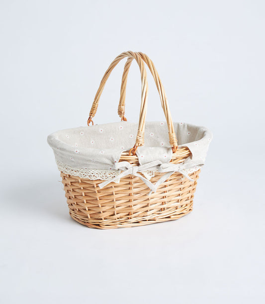 Handwoven oval wicker basket with double handles, light beige floral fabric lining, and lace trim