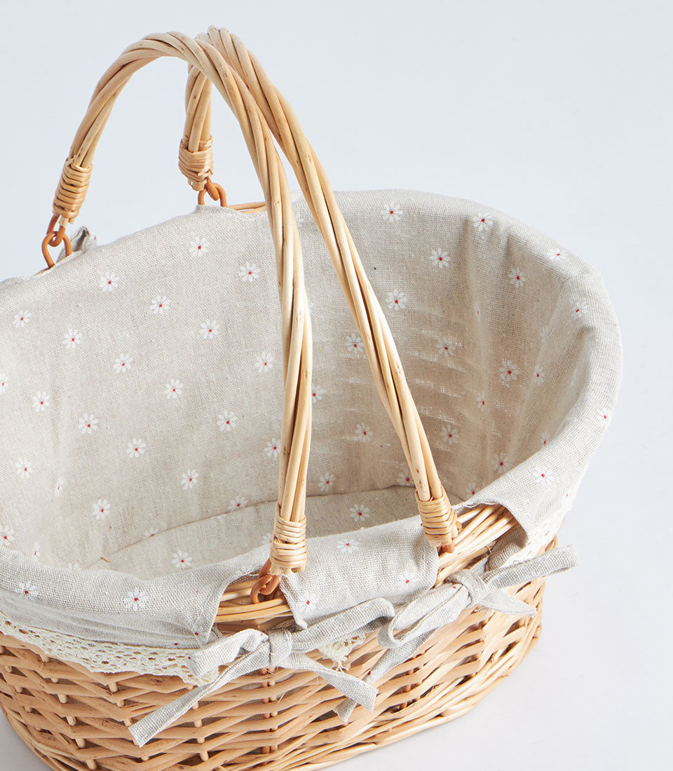 Light brown wicker oval basket with double handles and removable daisy-patterned fabric lining