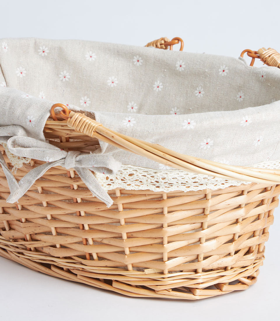 Light brown handwoven wicker basket with daisy-printed fabric lining and delicate lace trim