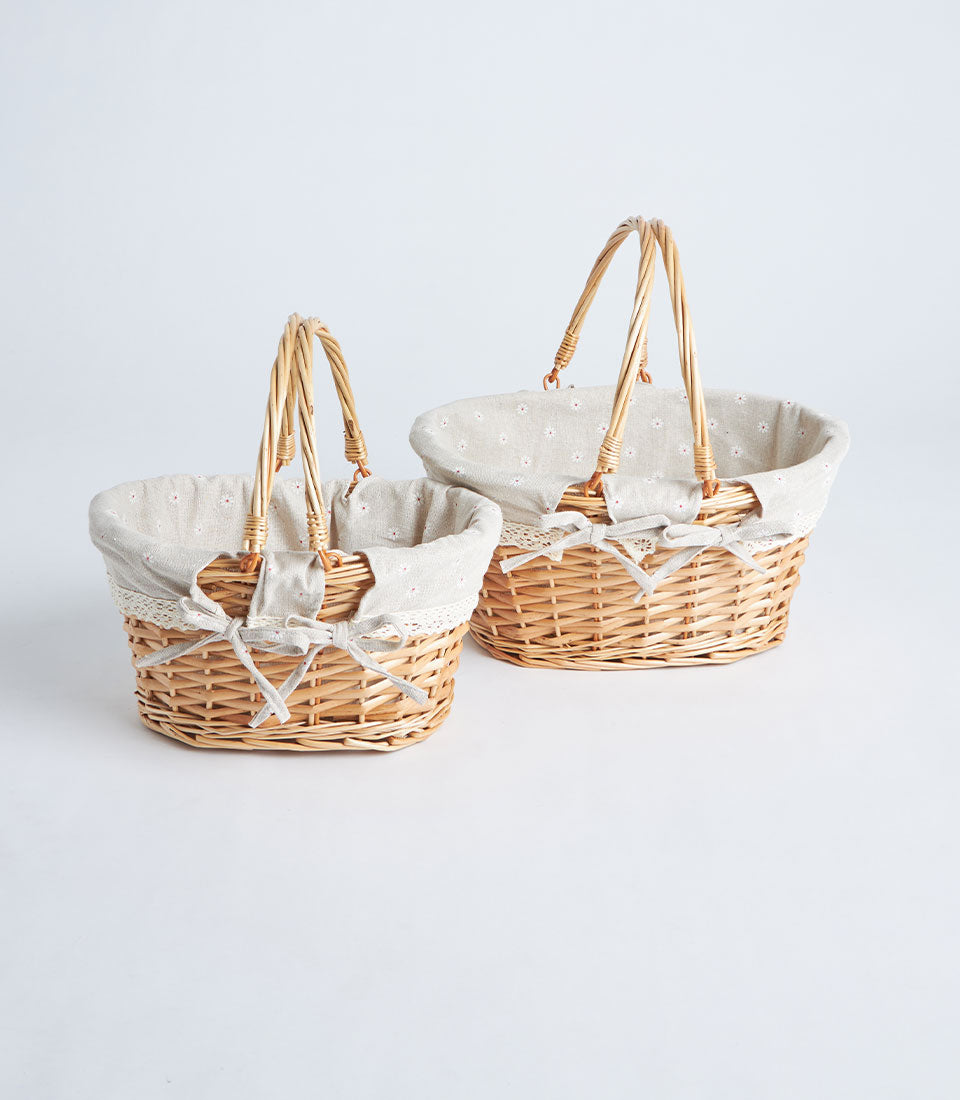 Light brown wicker gift baskets with double handles, beige floral fabric liners, and cream ribbon bows