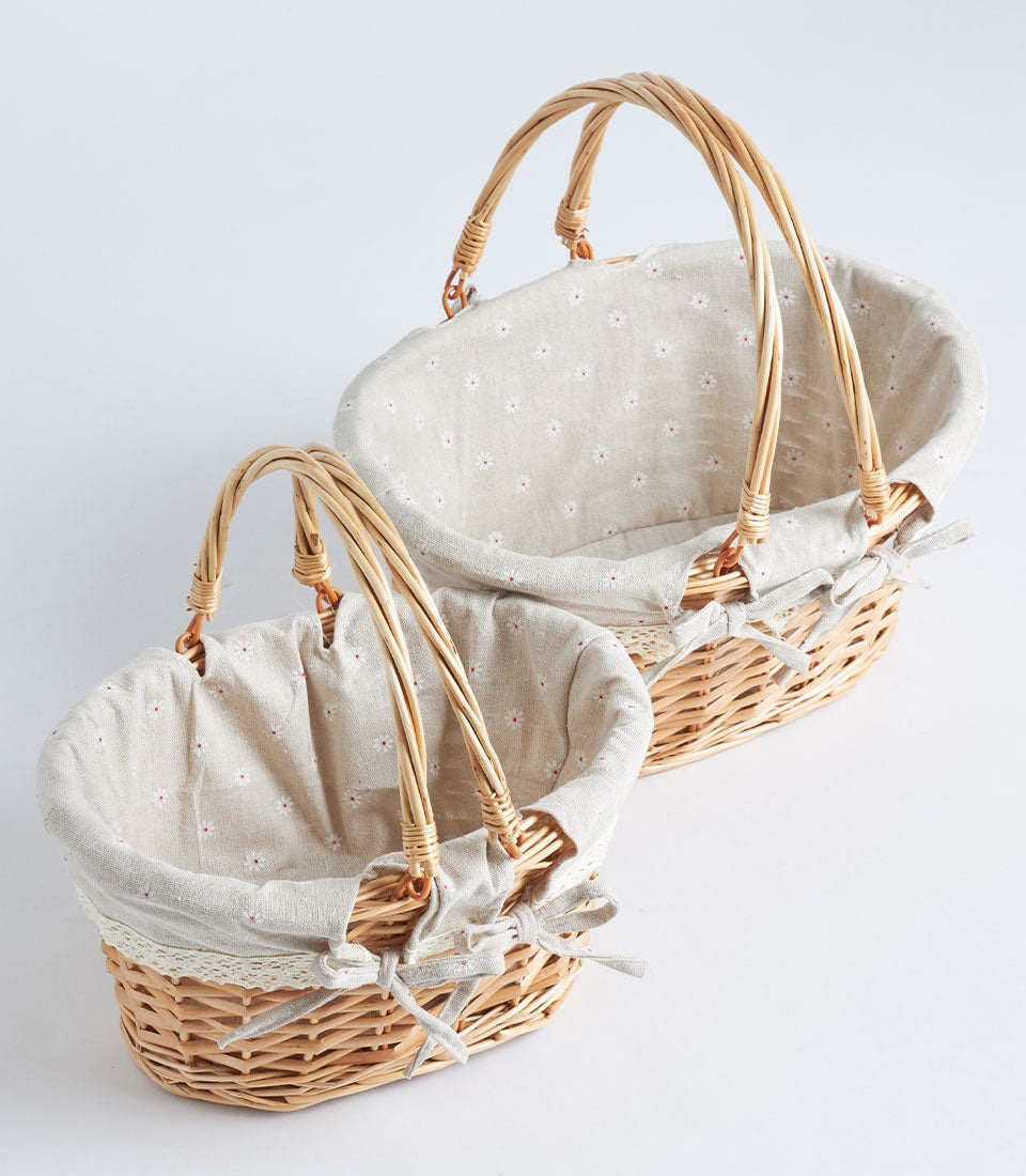 Handwoven oval wicker baskets with fabric liners, grey bows, and double handles for luxury gift hampers