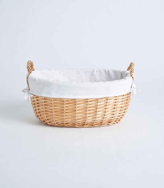 Large natural wicker oval basket with white linen lining and braided handles