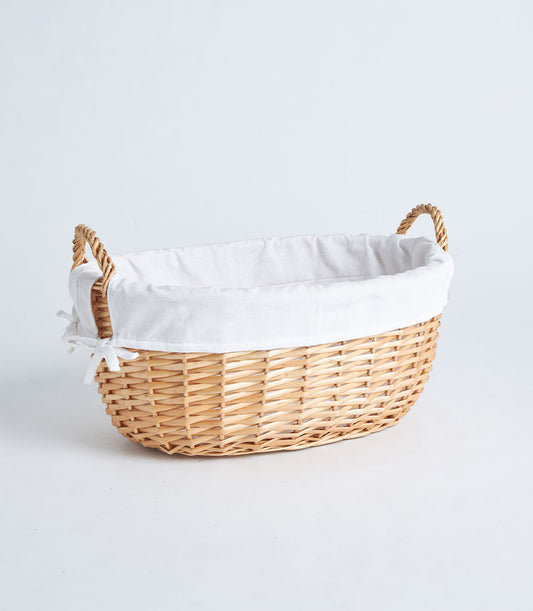 Large natural wicker oval basket with white linen lining and braided handles for curated gift hampers