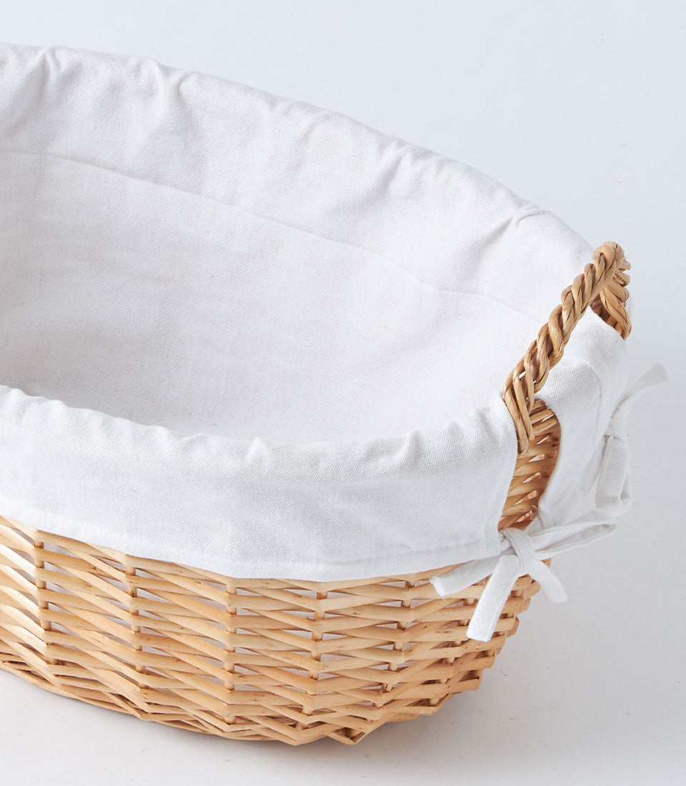 Large natural wicker oval basket with white linen lining and handles for gift hampers