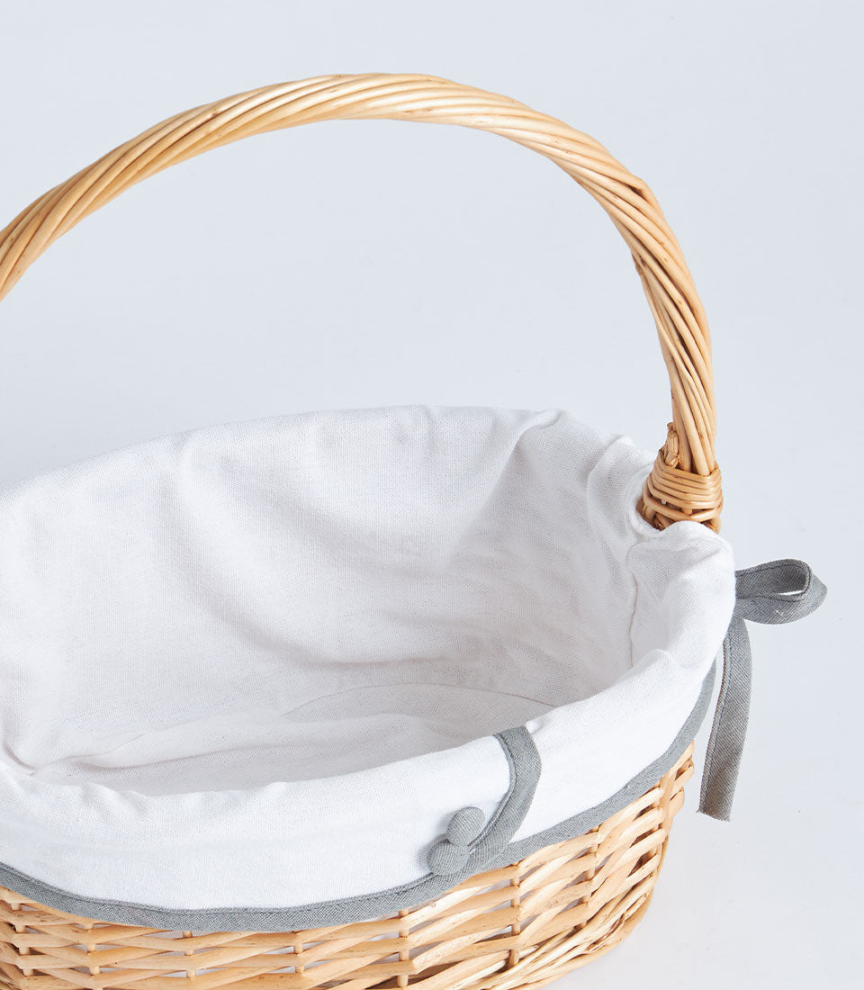 Light wicker oval basket with fabric-lined interior, grey trim, and decorative bow detail