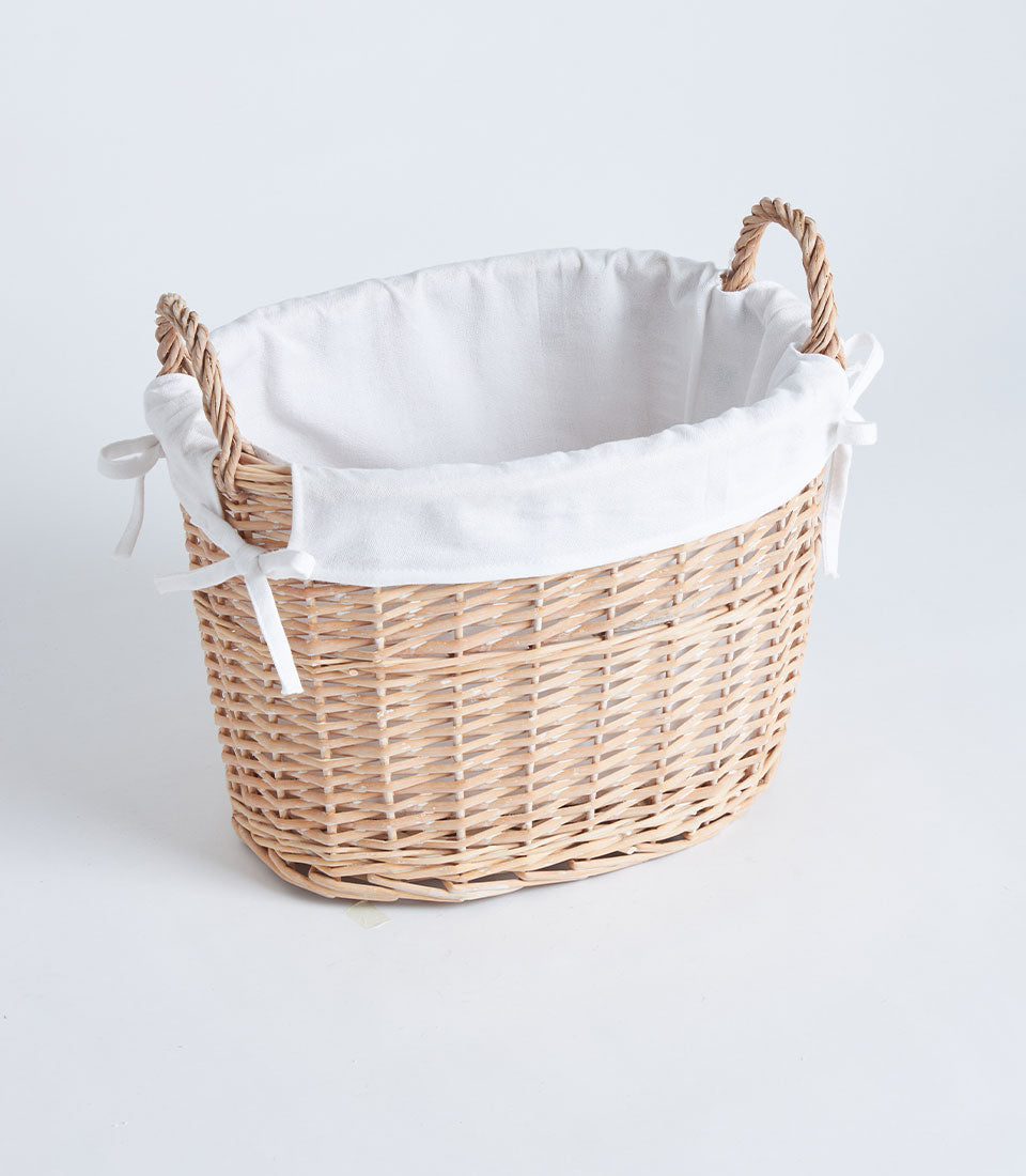 Natural wicker oval basket with white fabric lining and side handles for luxury gift presentation