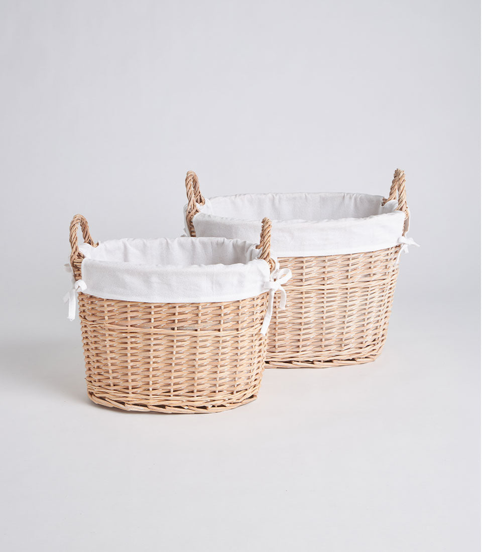 Handwoven natural wicker ovals with white fabric liners and braided handles, ready to fill with luxury gifts