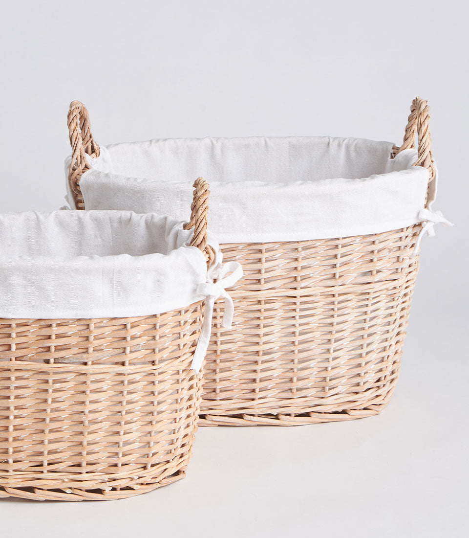 Natural wicker oval baskets with white fabric liners and twisted handles, ready for custom gift hampers
