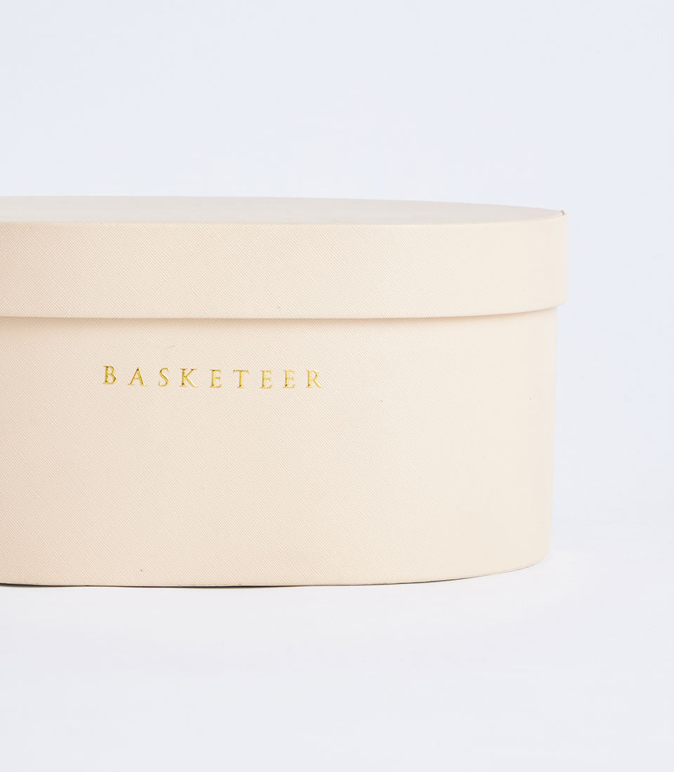 Beige leather round storage box with gold Basketeer branding and textured finish