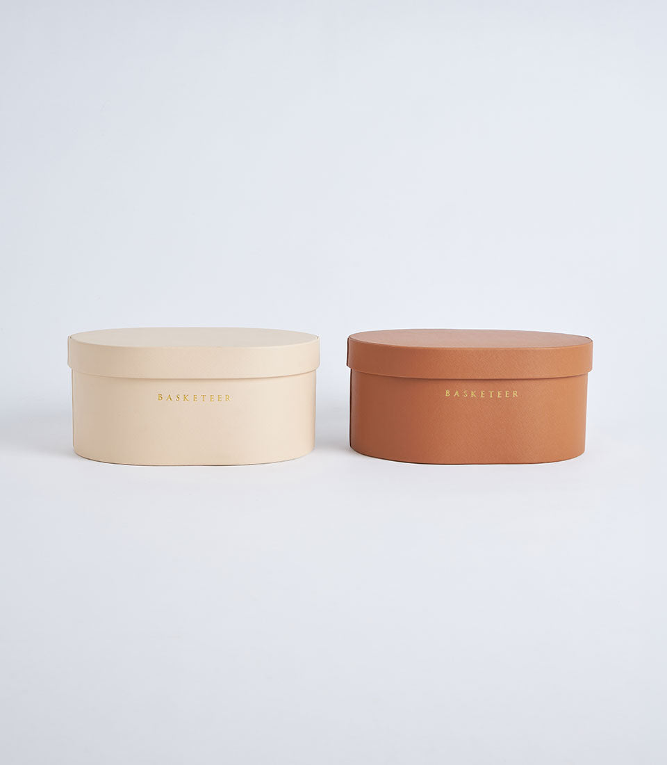 Beige and terracotta leather storage boxes with gold Basketeer branding, luxury gift packaging