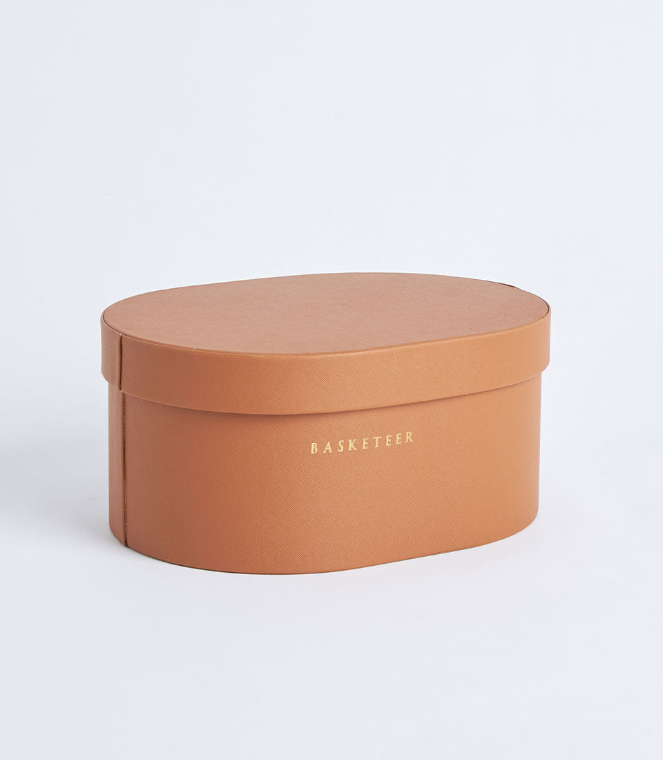 Oval brown leather storage box with gold embossed Basketeer branding and fitted lid