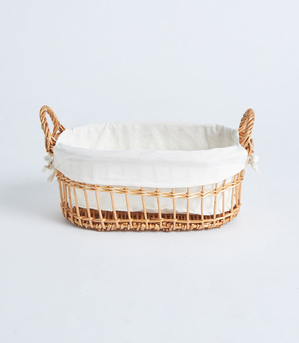 Natural woven wicker gift basket with rope handles and white fabric liner