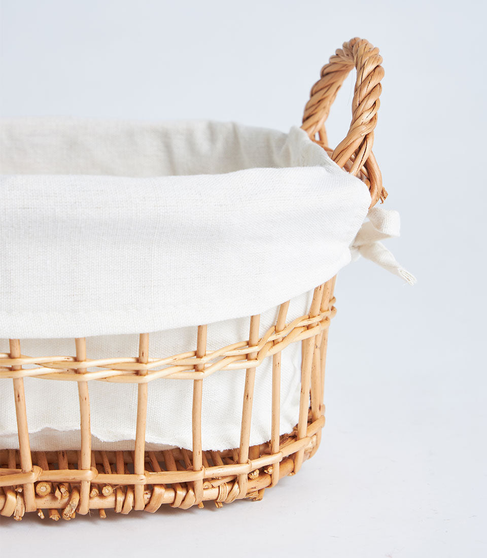 Natural wicker basket with white fabric liner and braided rope handles for luxury gift hampers
