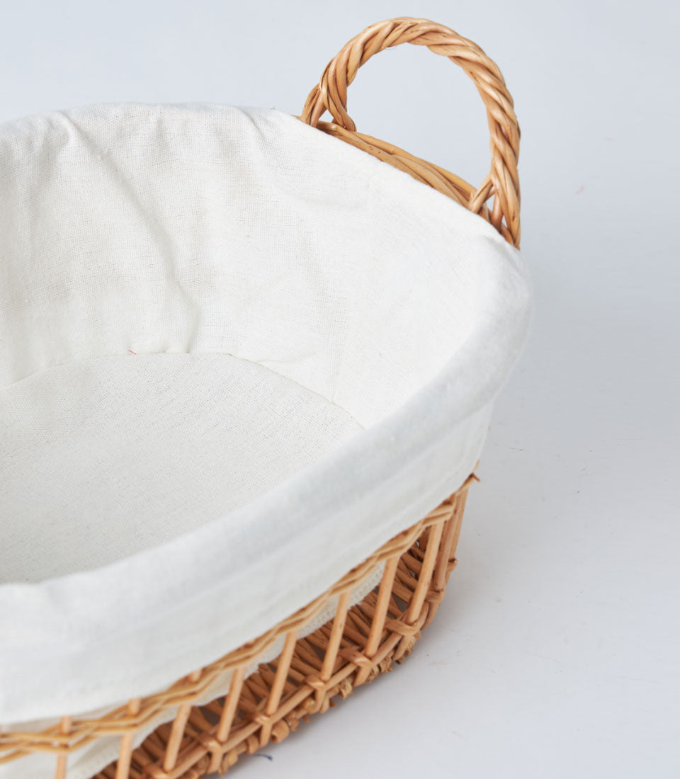 Natural wicker basket with cream linen liner and braided rope handles for luxury gift hampers