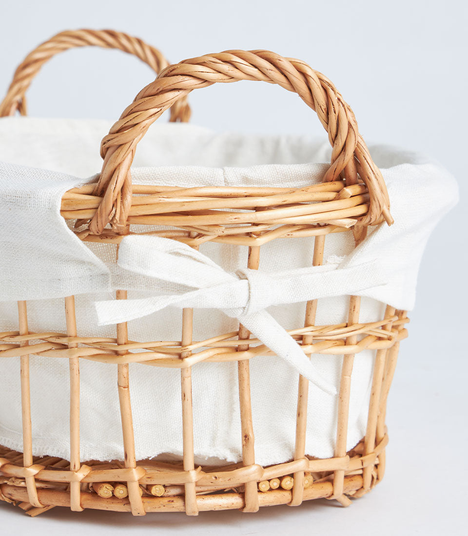 Light brown wicker basket with rope handles and white fabric lining for premium gift packaging