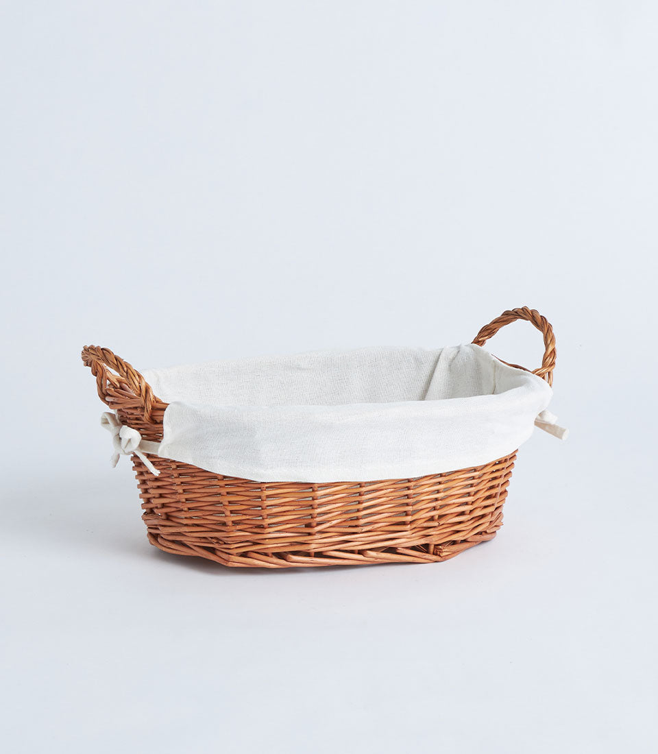 Natural wicker oval basket with cream linen lining and twisted handles
