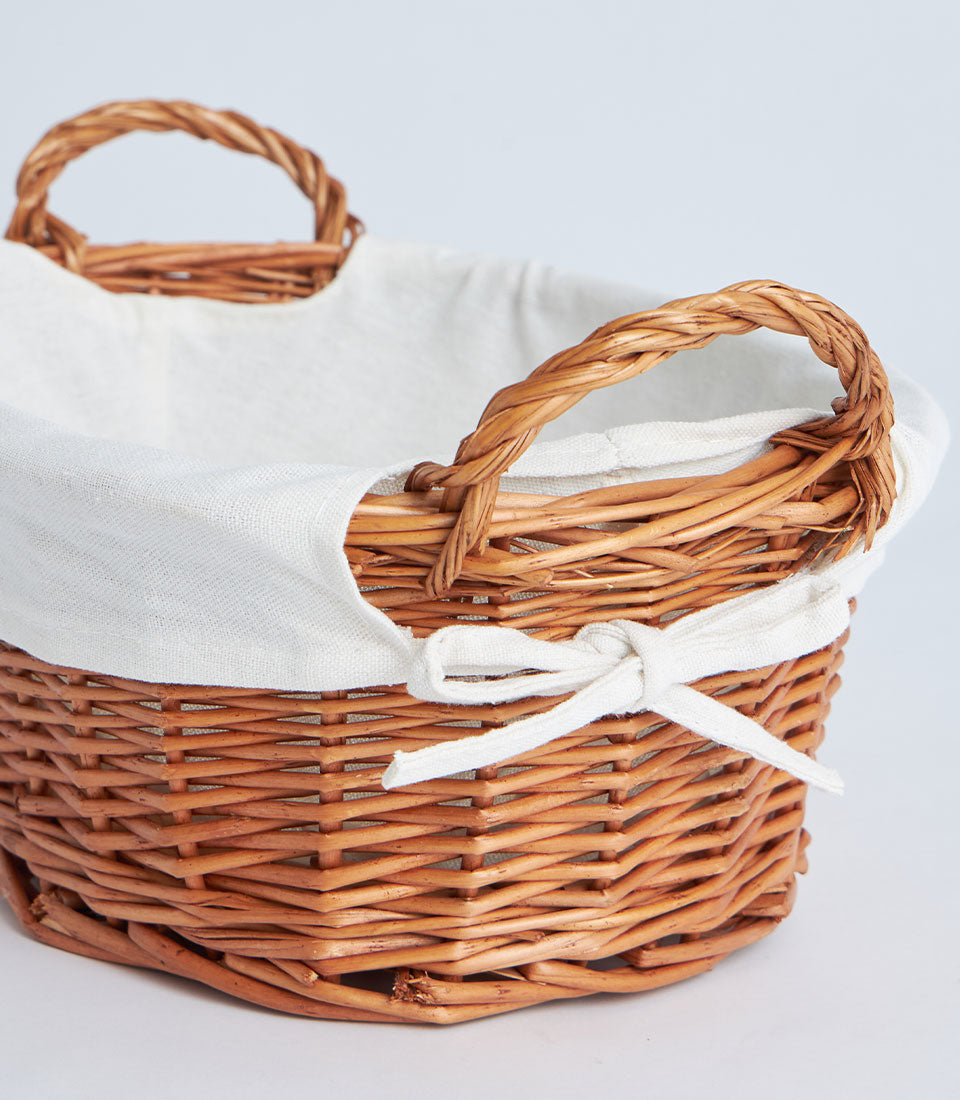 Rustic oval wicker basket with cream linen lining and braided handles