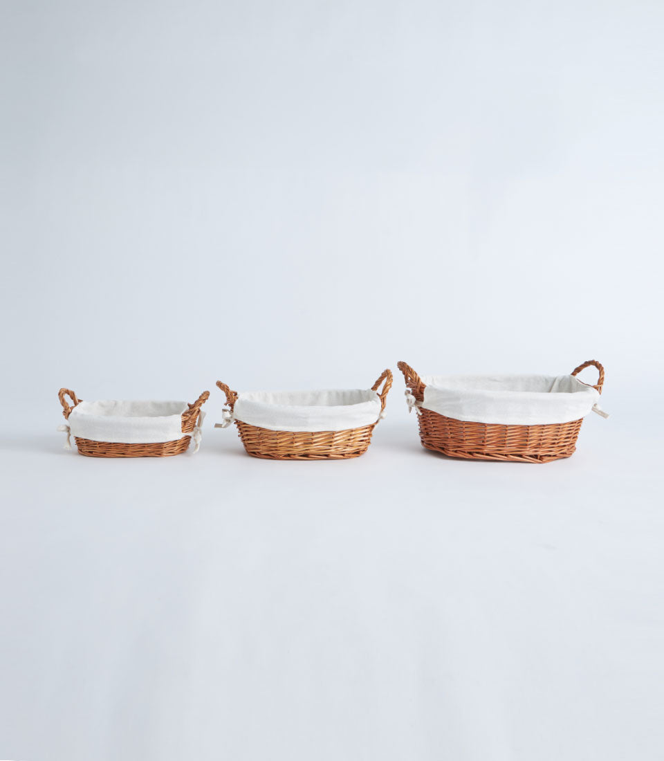 Natural wicker baskets with white linen liners and braided handles, three sizes for luxury gift hampers