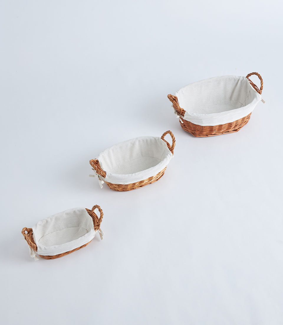 Nested wicker baskets with removable linen liners and braided handles in natural brown