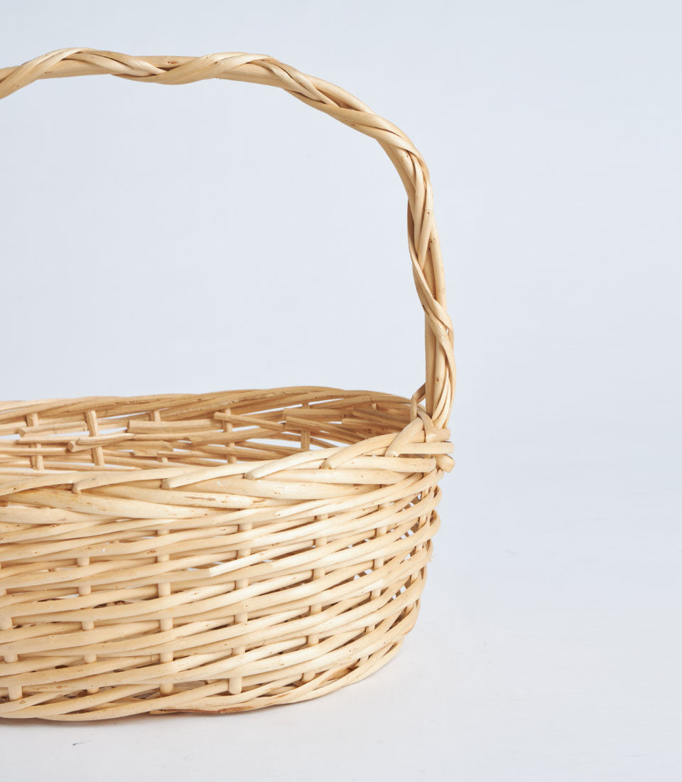 Natural wicker oval basket with twisted handle, light beige handwoven rattan