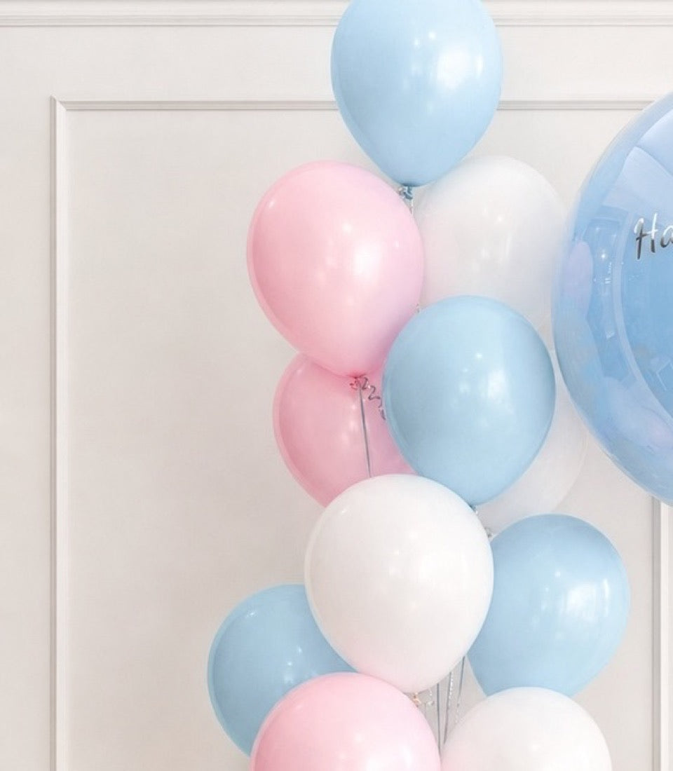 Pastel balloons in pink, white, and light blue arranged against a white wall and door frame, perfect for celebrations and events.